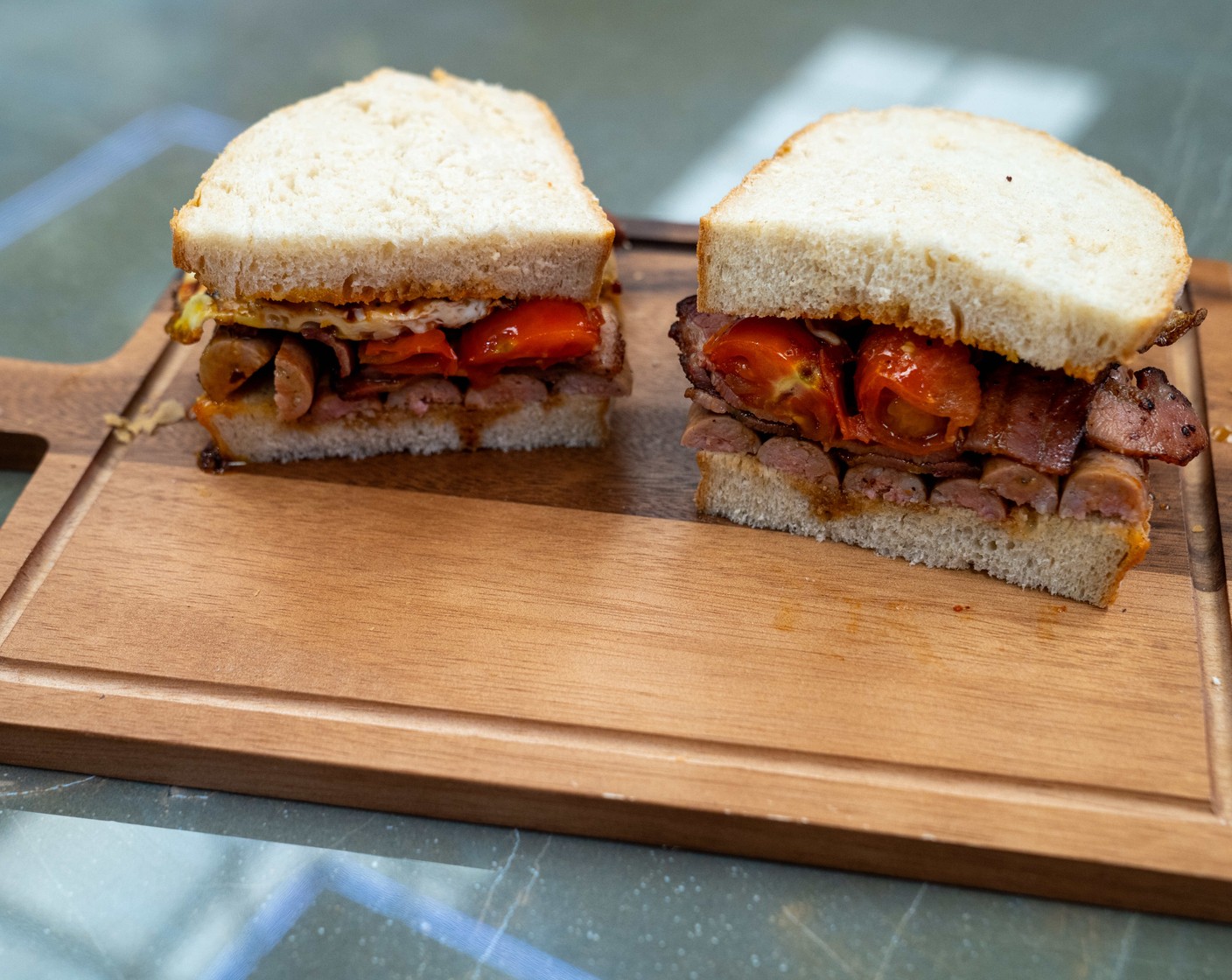 step 3 Assemble: Use a spoon to drizzle the fat from the eggs across the slices of bread. Cut the sausages in half and place on the bread along with the bacon. Drizzle the tomatoes with the Aged Balsamic Vinegar (1 tsp) and place on top of the bacon. Finish the sandwich with the fried eggs and remaining slice of bread.