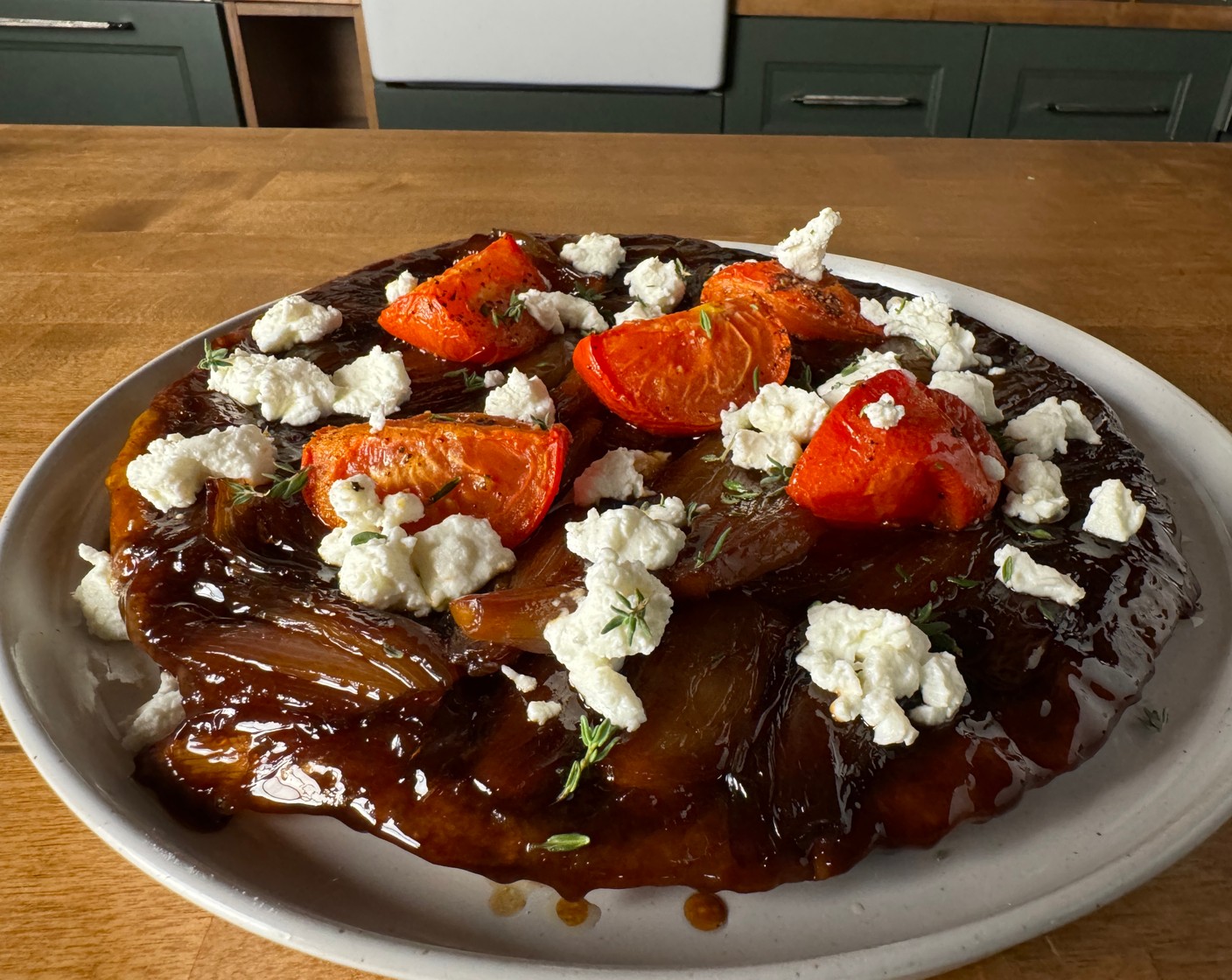 step 9 Invert the tatin onto a large plate. Arrange the tomatoes and Goat Cheese (1/2 cup) on top and finish with fresh thyme leaves.