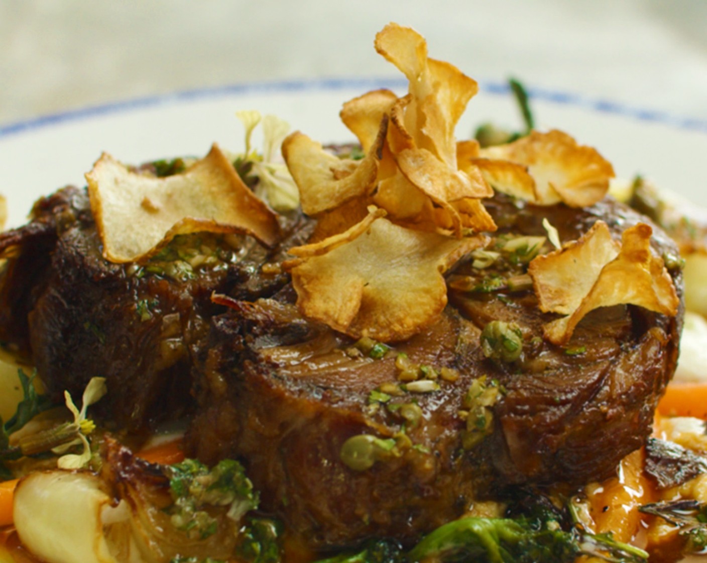 step 24 To serve, spoon a heaping serving of puree onto a warm plate. Toss buttered vegetables with Fresh Herbs (1 handful) and nestle into puree. Top with a slice (or two) of crispy lamb confit followed by a generous drizzle of salsa verde and sunchoke chips.