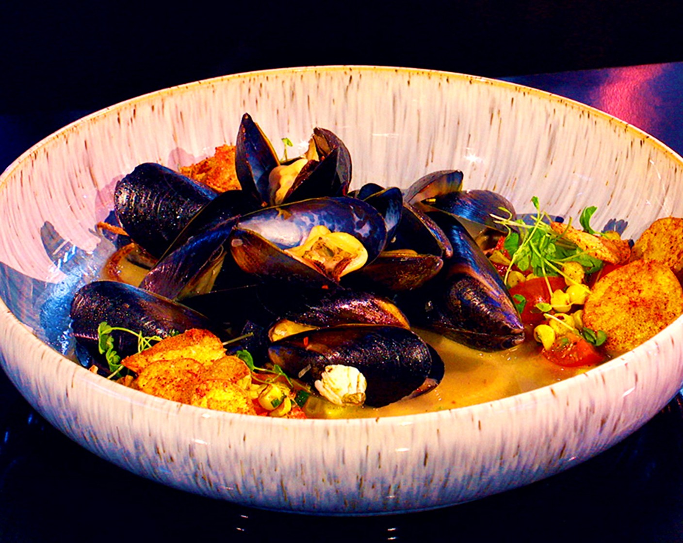 step 9 To serve: Spoon the corn salsa around the plate and arrange the mussels in the center. Pour the broth in the center and garnish with the potato chips and Microgreens (to taste).