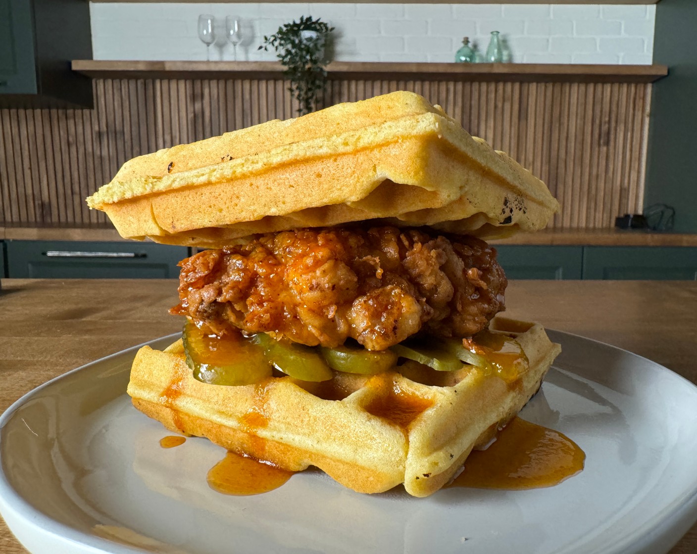 step 9 Assemble: Place the fried chicken between two waffles, top with Pickle Slices (to taste) and drizzle with the honey maple syrup.